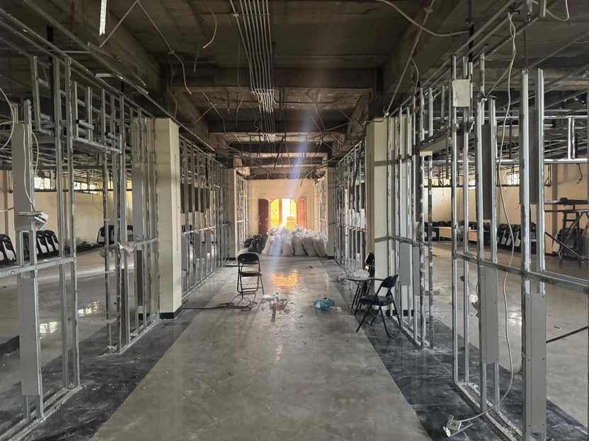 Progres konstruksi interior yang memperlihatkan rangka partisi dan utilitas plafon.