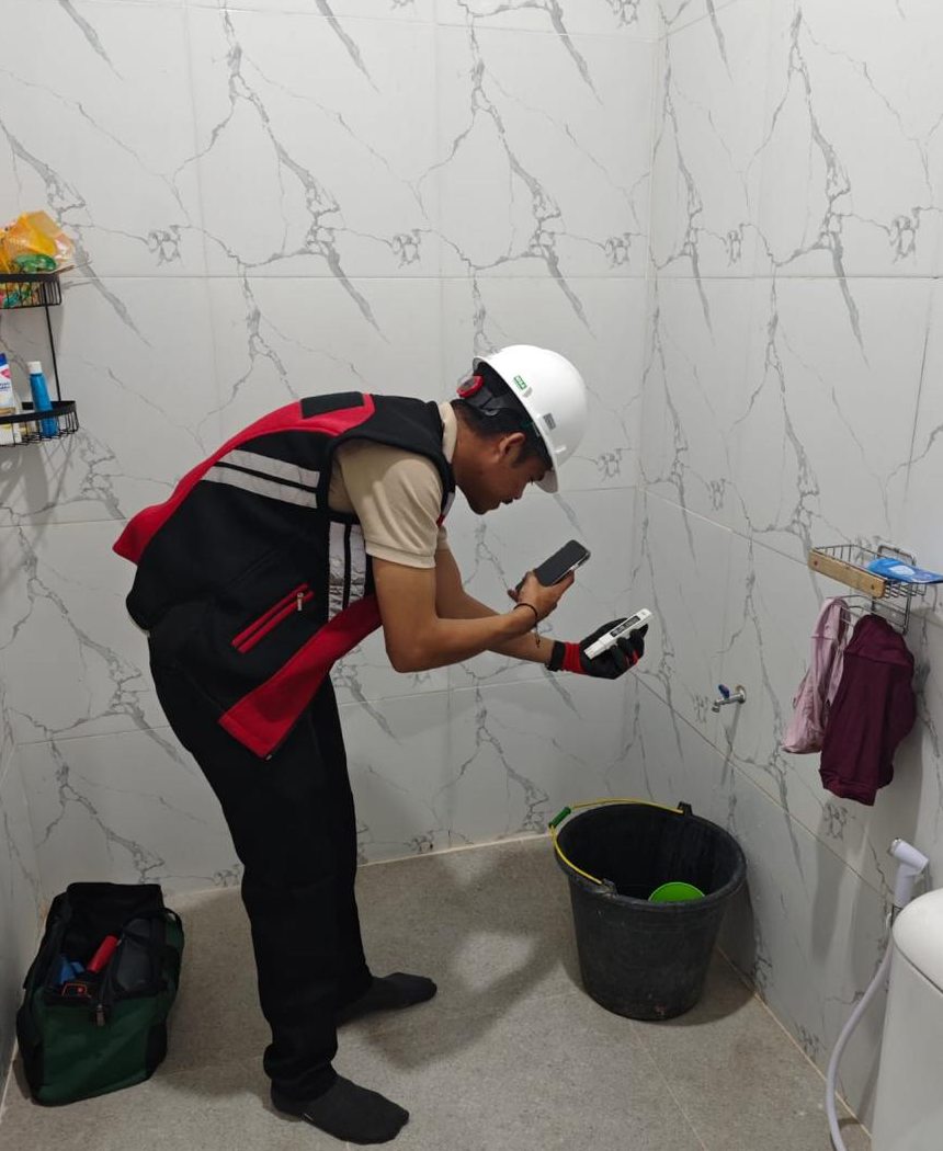 Field survey documenting an existing bathroom with measurement tools.