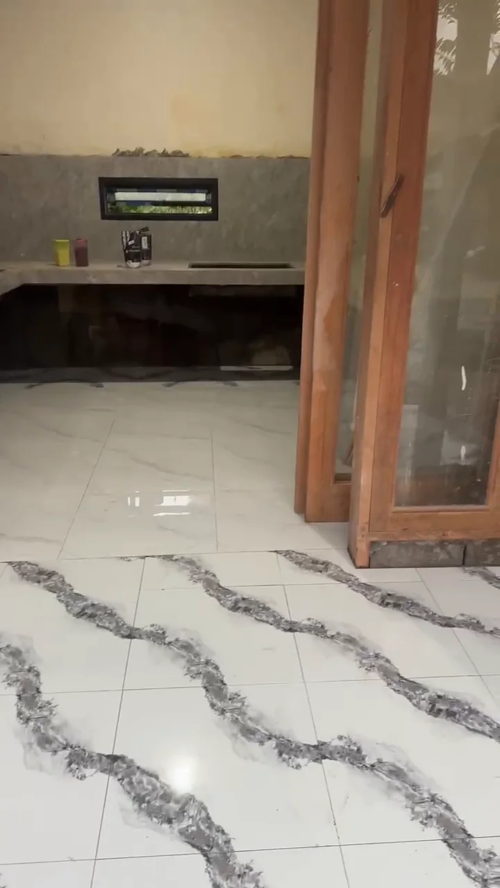 View through the timber-and-glass doorway toward the kitchen counter and newly laid floor, before cabinetry installation.