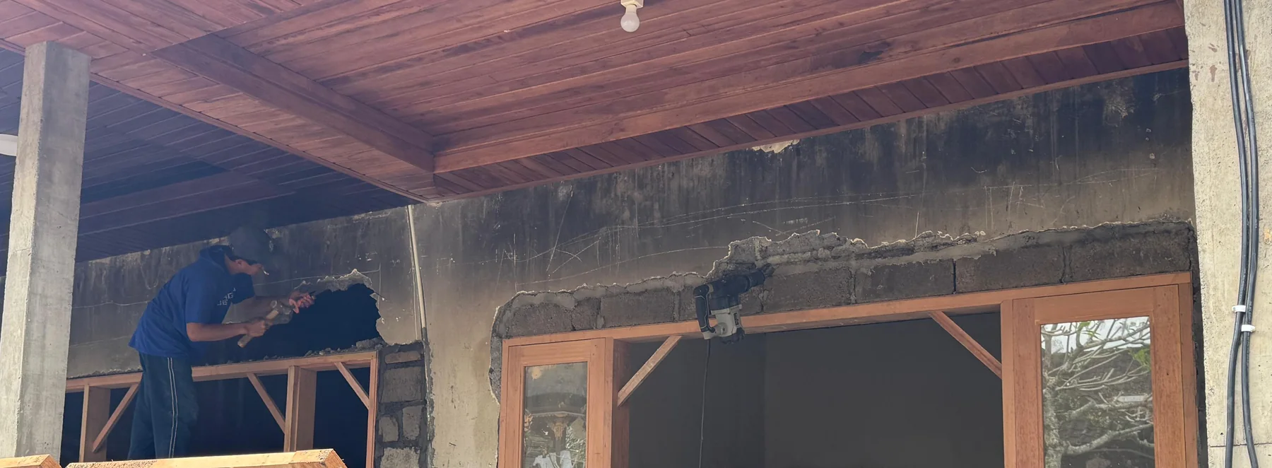 Existing wall opening being modified above timber frames under the retained timber ceiling.
