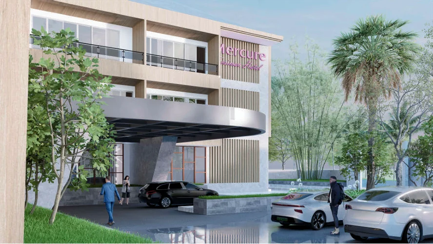Ground-level perspective of the hotel entrance canopy and guest-room balconies.
